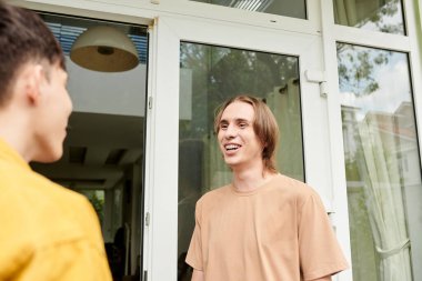 Gülümseyen genç adamlar favori kafelerinin önünde konuşuyorlar.