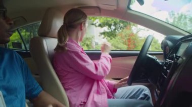 Kadın öğrencilerin günlük kıyafetlerini giyip araba sürmeye hazırlanmaları, arabada eğitmenin yanında emniyet kemerini takmaları.