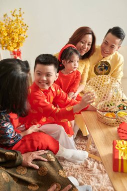 Neşeli küçük çocuk evdeki Tet kutlamasında kuru meyve yiyor.