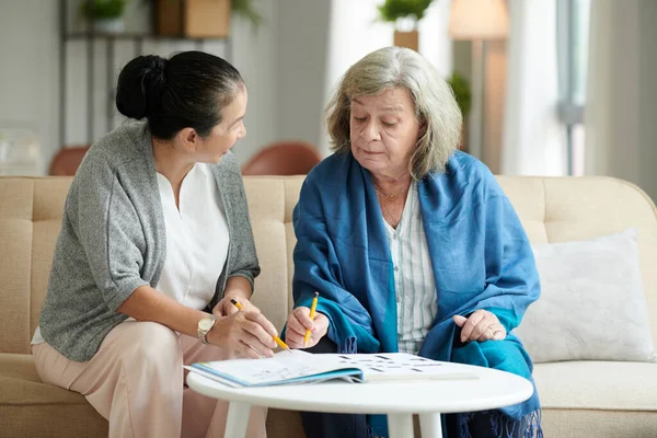 疗养院休息区老年妇女在餐桌上解开纵横字谜 — 图库照片