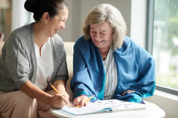 Ältere Frauen Lachen Wenn Sie Hause Kreuzworträtsel Lösen — Stockfoto