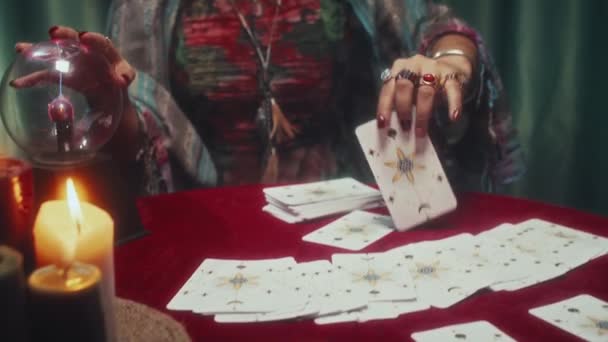 从塔罗牌布局中拿出一张卡片 在透视过程中对着镜头的妇女倾斜的照片 — 图库视频影像