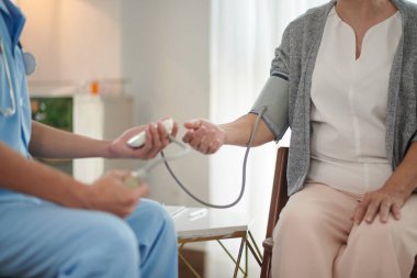 Sağlık çalışanı kan basıncını ölçmek için yaşlı kadının evine geldi.