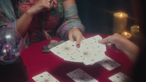 セッション中にテーブルに座っている間 女性にレイアウトから1枚のタロットカードを取るように要求するフォーチュンテラーの撮影 — ストック動画