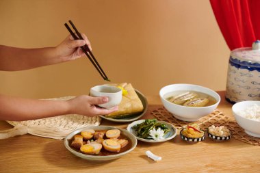 Yemek çubuklarıyla yemek masasından geleneksel Vietnam yemeklerini alan birinin elleri.