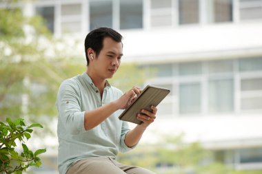 Tablet bilgisayarlı genç Asyalı girişimci iş arkadaşını arıyor