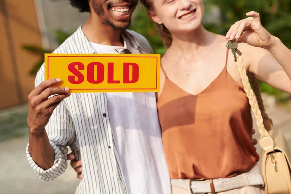 ハッピーなカップルが家を購入した後に販売サインを保持しているのクロップされたイメージ — ストック写真