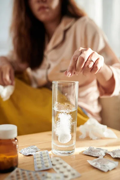 Woman sick with seasonal flu drinking water with aspirin
