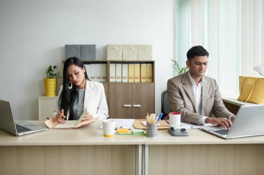 Ciddi iş adamları modern ofiste masa başında çalışmaya odaklandılar.