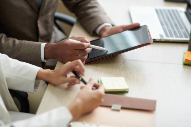 İş adamlarının elleri tablet bilgisayarda yaklaşan durgunluk konulu makaleyi tartışıyor