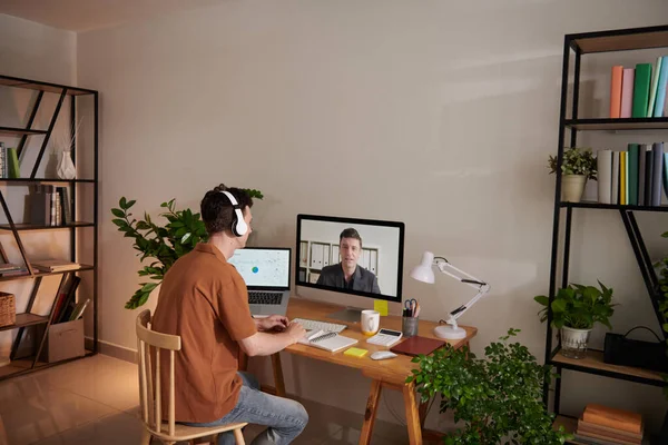 Young man talking to colleague during online meeting when working from home