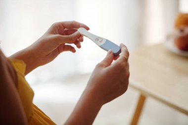 İki şeritli hamilelik testi tutan kadının elleri.