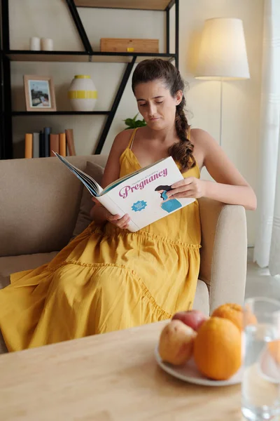 Młoda Kobieta Odpoczywająca Kanapie Domu Czytająca Książkę Ciąży — Zdjęcie stockowe