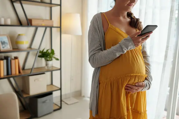 スマートフォンでアプリケーションを介して医師の任命を行う妊婦のクロップ画像 — ストック写真