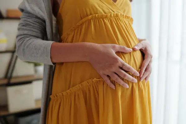 妊娠中の女性は腹に手を置くときに心のジェスチャーを作ります — ストック写真