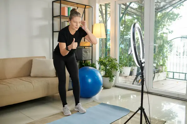 Fitness instructor recording workout video for her clients at home