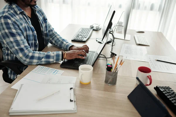 Ofis masasındaki dizüstü bilgisayardaki yazılım geliştiricisinin kırpılmış resmi