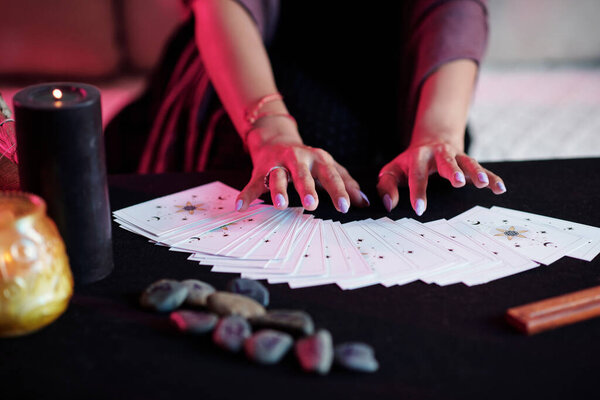 Closeup image of seer holding hands over tarot cards when predicting future