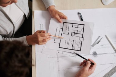 Mimar ve iç mimarın elleri apartman planlarını tartışıyor, yukarıdan manzara