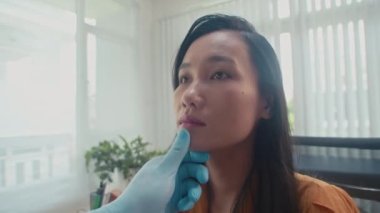 Klinikte estetik cerrah tarafından muayene edilen Asyalı kadınların yüzlerini kapatın.