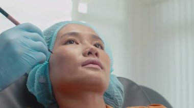 Klinikte yüz gerdirme ameliyatı için kadın yüzü gösteren tıbbi eldivenli doktorun elini kapat.