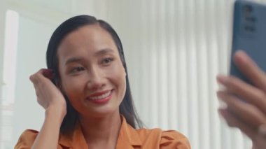 Klinikteki güzellik prosedüründen sonra cep telefonuyla selfie çeken Asyalı genç bir kadın.