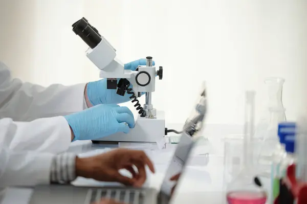 Hands of researcher looking at human tissue with microscope