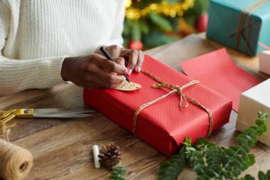 Siyah kadının elleri Noel hediyelerini paketliyor ve imzalıyor.