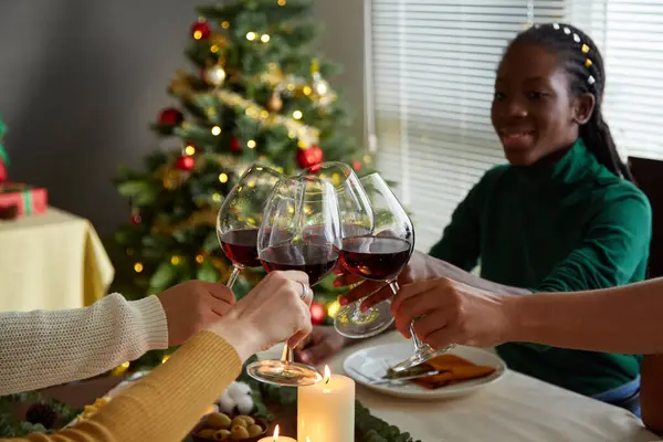 Group of happy friends toasting with wine glasses over Christmas table