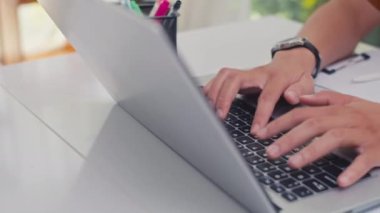 Bilgisayarı kullanan ve evde ders çalışırken not alan tanınmayan bir adamın ellerini kapatın.