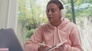 Kulaklıklı kız öğrencinin evden gelen video görüşmesi sırasında öğretmenle konuşmasını çek.