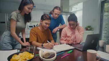 Çok kültürlü kolej öğrencilerinden oluşan orta ölçekli bir grup projeyle ilgili fikirleri tartışırken evde birlikte hazırlanıyorlar.
