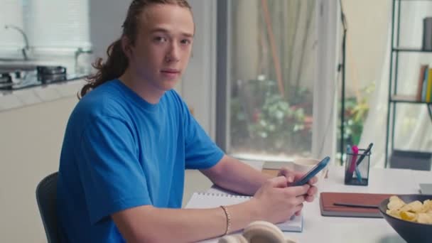 Retrato Estudiante Masculino Positivo Con Pelo Largo Usando Teléfono Inteligente — Vídeos de Stock