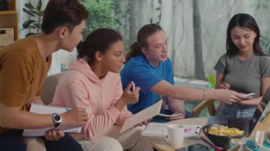 Genç adamın evde arkadaşlarıyla toplanan derslere hazırlanırken ekrandaki kablosuz bilgisayarı işaret ettiği orta boy bir çekim.
