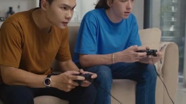 Evdeki konsolu kullanarak video oyununda kazandıktan sonra sevinen iki genç adamın orta boy fotoğrafı.