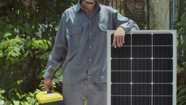 戴硬礼帽 靠在太阳能电池板上 看着相机的快乐工程师的倒立画像 — 图库视频影像