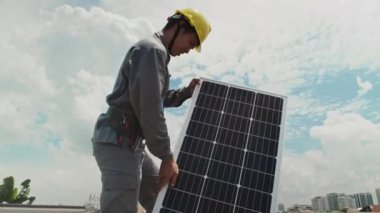 Sarı başlıklı mühendisin müşteri evinin çatısına güneş paneli kurarken orta uzunlukta bir görüntüsü.