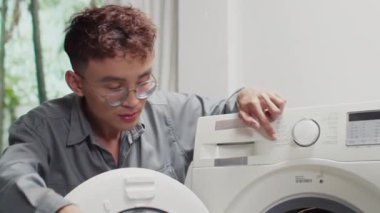 Erkek tesisatçıların orta ölçekli görüntüsü. Bozuk çamaşır makinesinin kapalı alanda nasıl tamir edileceğini tartışıyorlar.