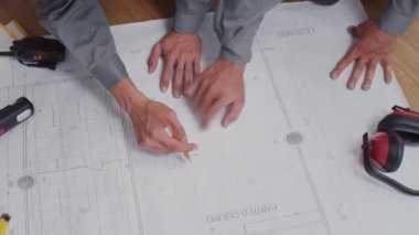 Üniformalı mühendislerin evle ilgili planlara bakarak yenileme planlarını tartıştığı yüksek açı görüntüsü