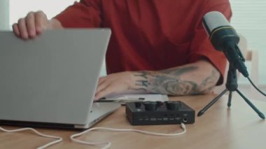 Stüdyoda podcast 'e hazırlanırken ses ekipmanlarını ve laptopunu bağlayan bir adam görüntüsü.