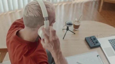 Stüdyoda kayıt için hazırlanırken sesi ayarlayan ve kulaklık takan podcaster görüntüsü yüksek açılı