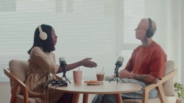 Podcast 'in kadın sunucusu ve erkek konuğu stüdyoda el sıkışıyor.