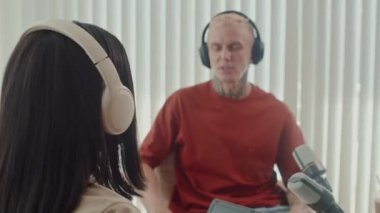 Stüdyoda podcast yaparken erkek misafirlerin iş konuşmalarını dinleyen bir kadının omzunun üstünden.