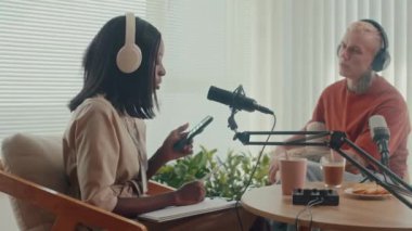 Stüdyoda kayıt yaparken erkek konuğuyla farklı konuları tartışan kadın podcaster görüntüsü.