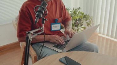 Erkek basın temsilcisini mikrofona konuşurken ve stüdyoda röportaj sırasında dizüstü bilgisayar kullanırken çek.