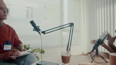 Kadın girişimci ve podcast sunucusunun stüdyodaki görüşme sırasında masada otururken orta uzunlukta görüntüsü.