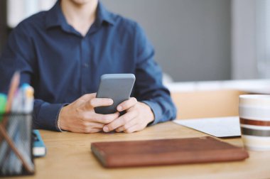 Genç girişimci ofis masasında oturuyor ve sosyal medyada haberlere bakıyor.