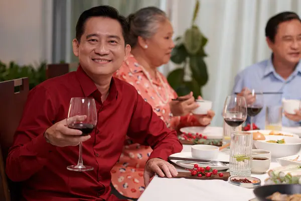 Cheerful Mature Vietnamese Man Drinking Glass Wine Dinner Table His — Stock Photo, Image