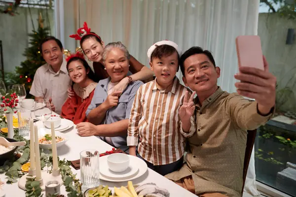 Big Vietnamese family posing for selfie at Christmas dinner table