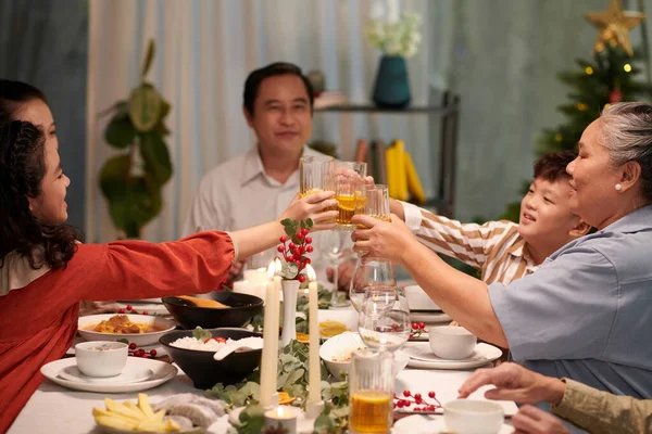 Family members toasting with glasses of ice tea over dinner table